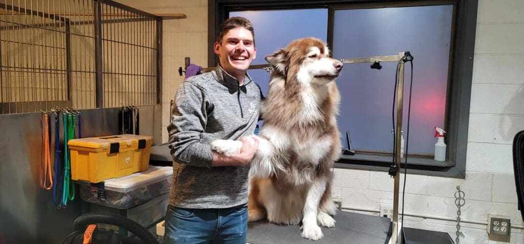 Dog groomer smiling with a dog